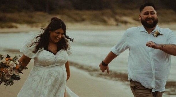 Couple in wedding attire happily runs on Corindi Beach near Labelleame Aesthetics, New South Wales, AU.