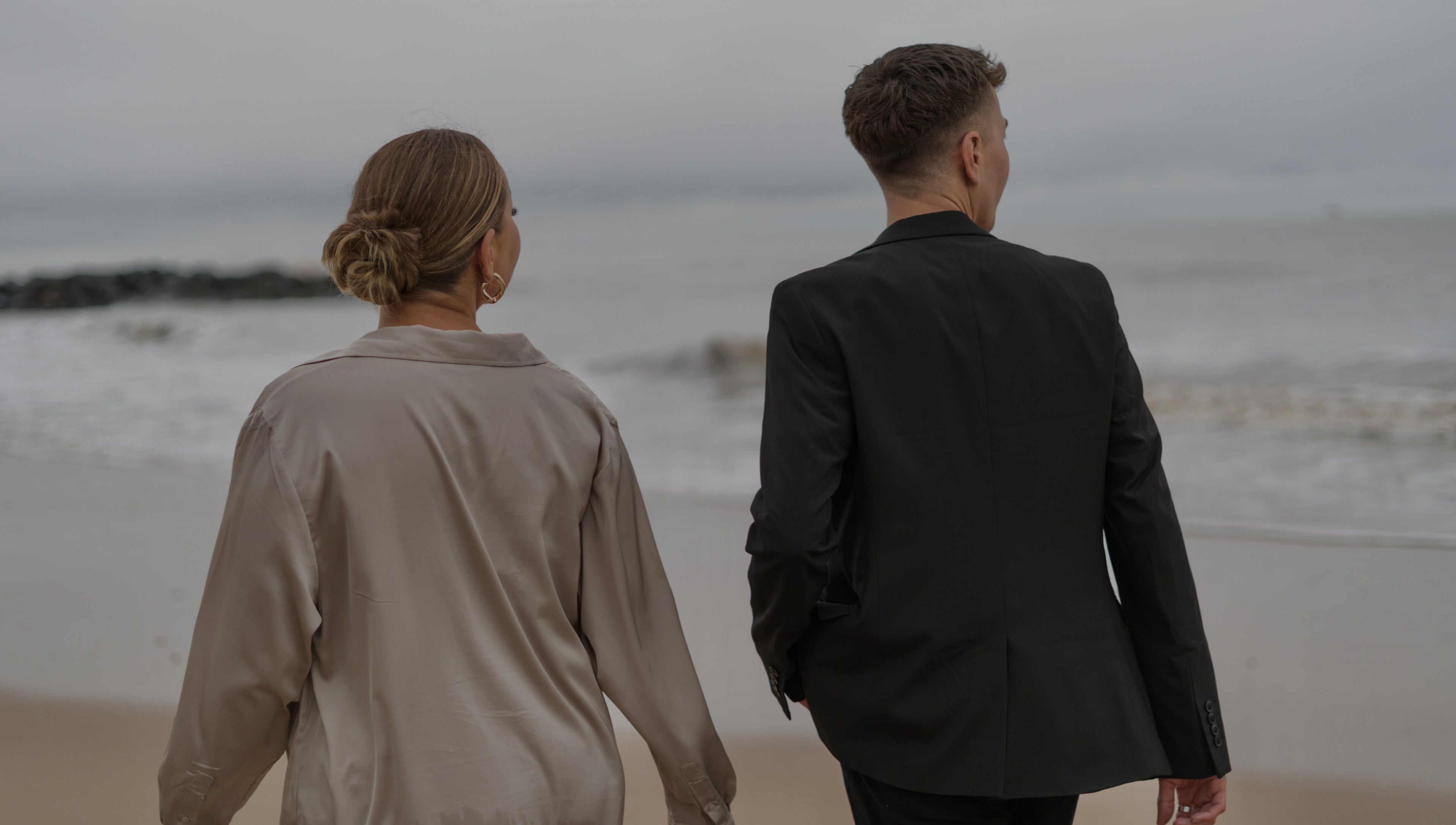 Elegant couple strolling along a serene beach near V O S, Beccles, England, GB.