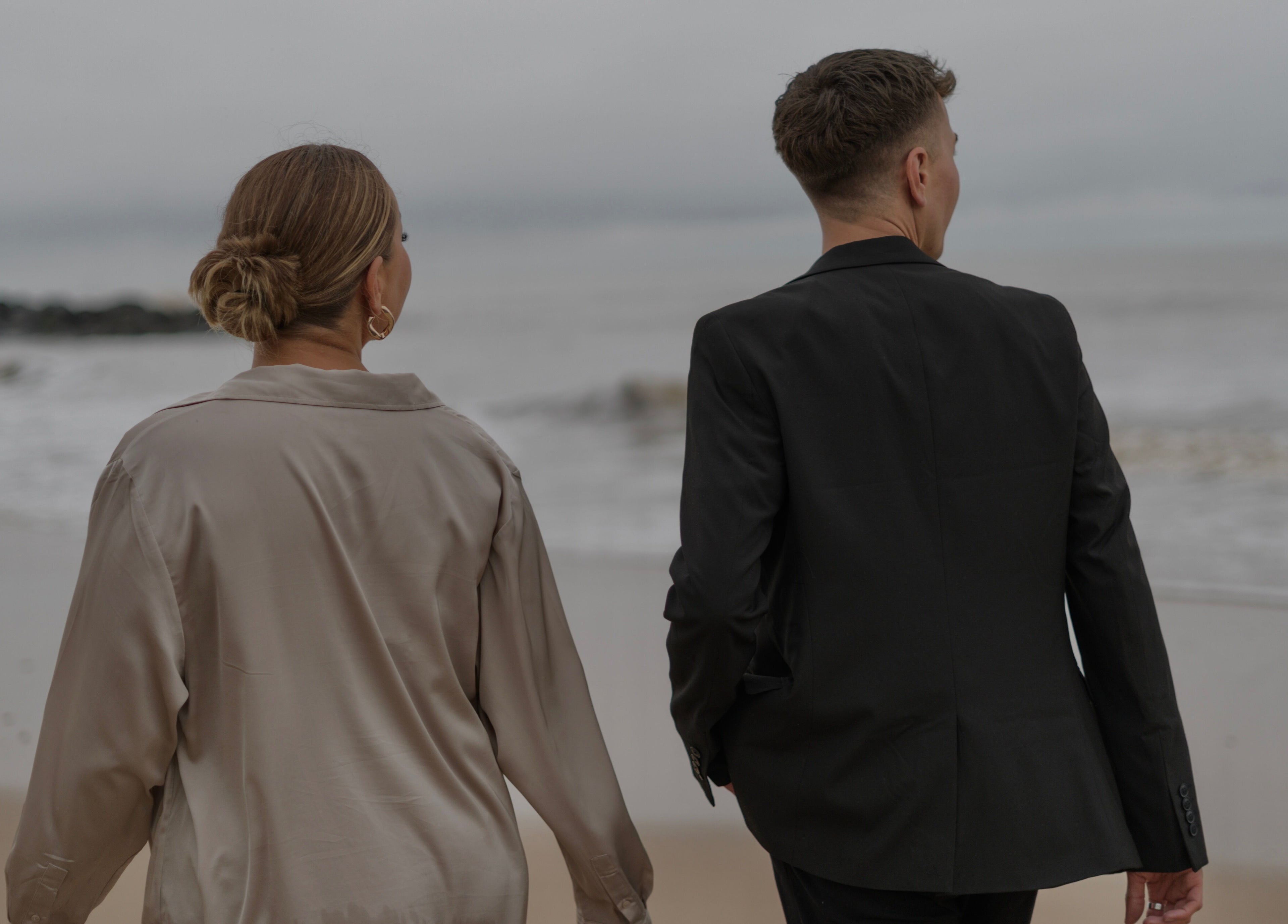 Elegant couple strolling along a serene beach near V O S, Beccles, England, GB.