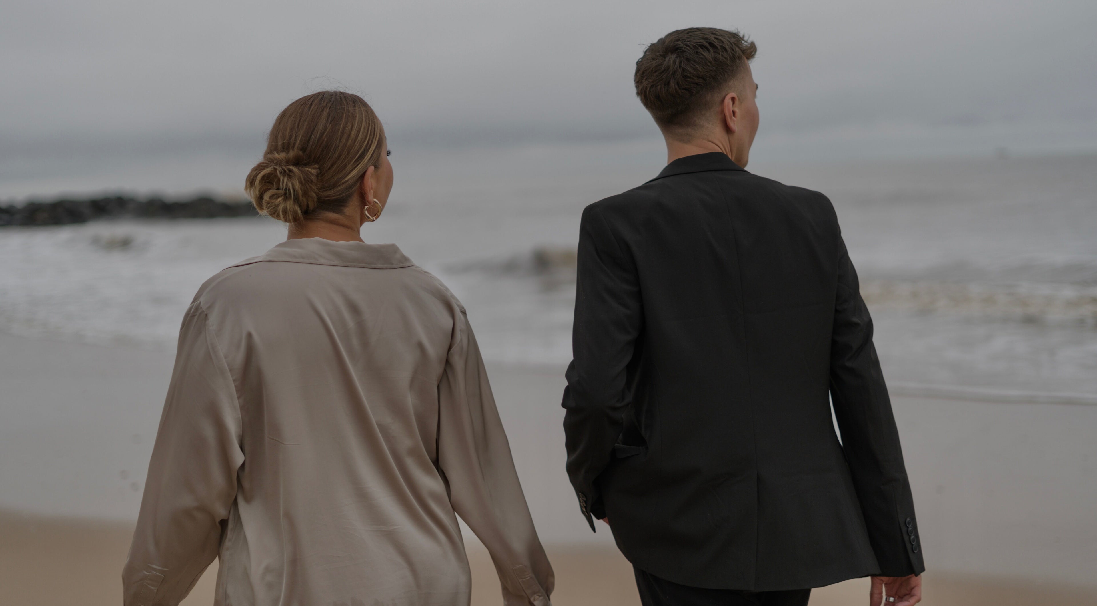 Elegant couple strolling along a serene beach near V O S, Beccles, England, GB.