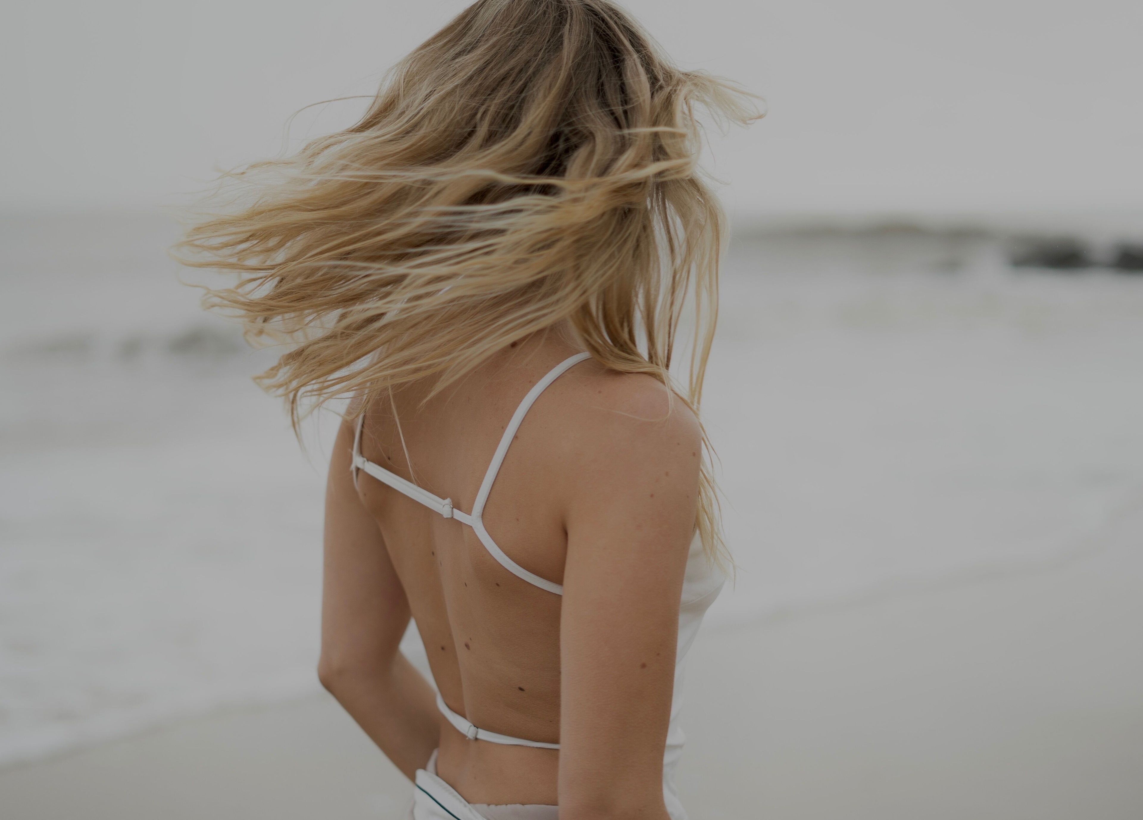 A woman with flowing hair on a beach near V O S, Beccles, England, GB, epitomizing natural beauty.
