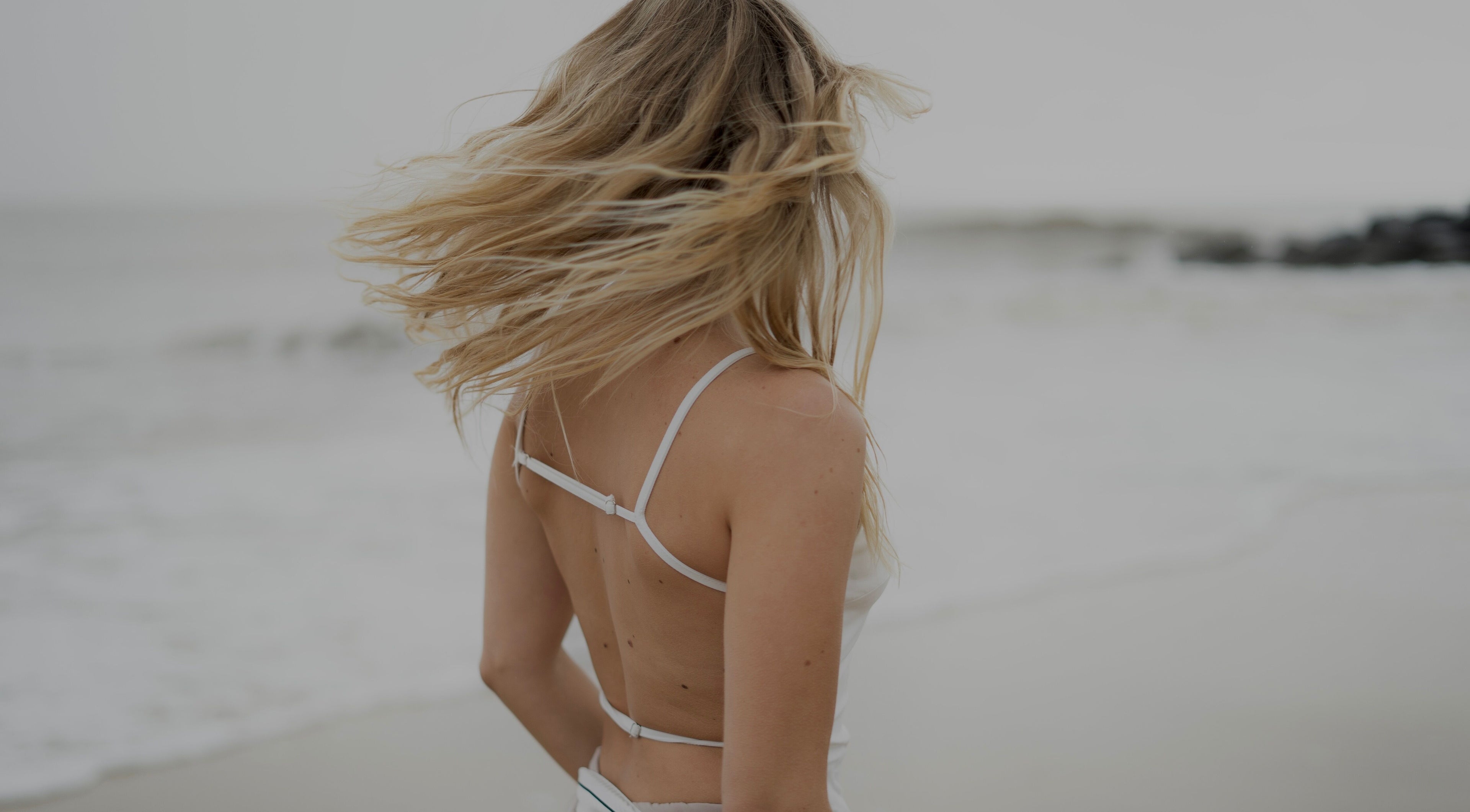 A woman with flowing hair on a beach near V O S, Beccles, England, GB, epitomizing natural beauty.