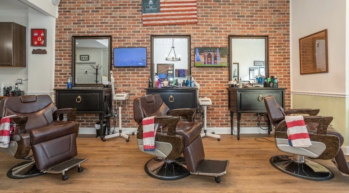 Interior of The Presidents Club Barber Shop in New Jersey with vintage chairs and brick walls.