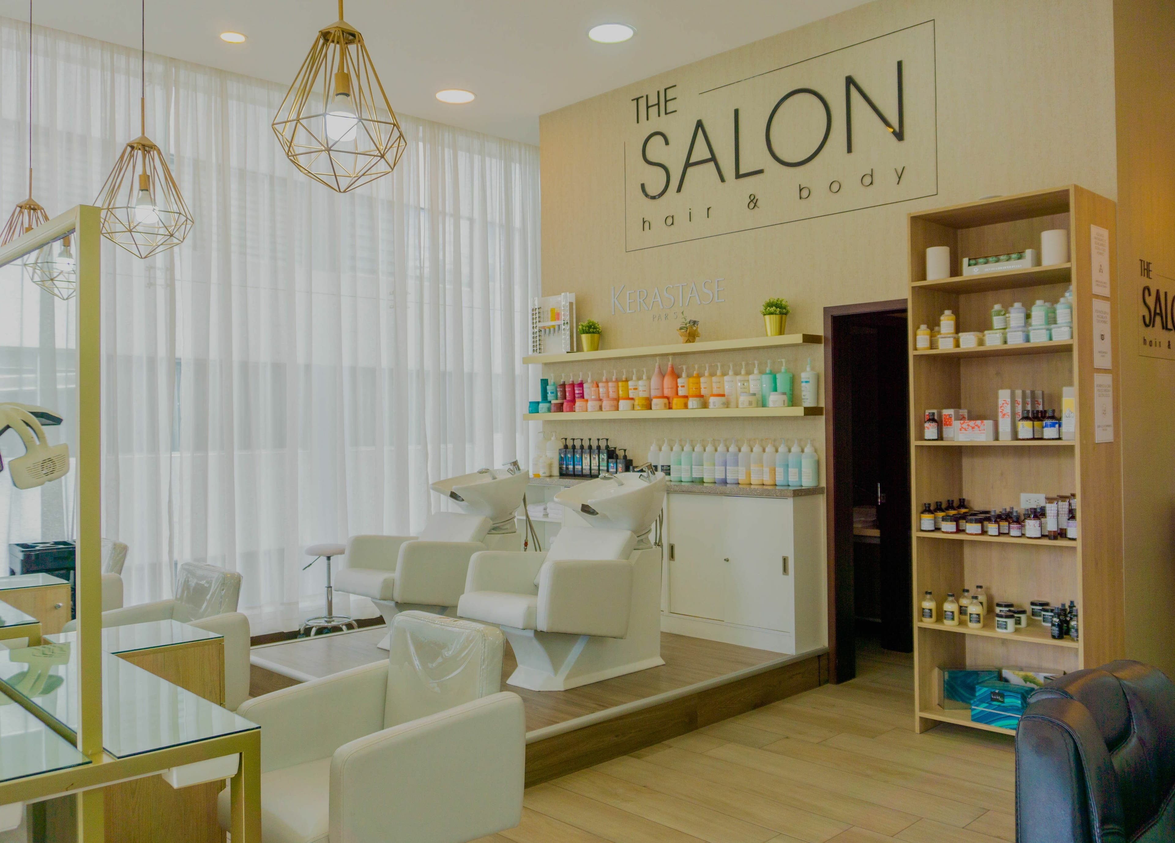 Interior elegante de The Salon en Quito, Pichincha, EC, con sillas blancas y productos profesionales de belleza.