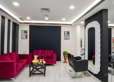 Sophisticated lounge at Beauty Lounge, Salmiya, Hawalli Governorate, KW with vibrant red sofas and modern décor.