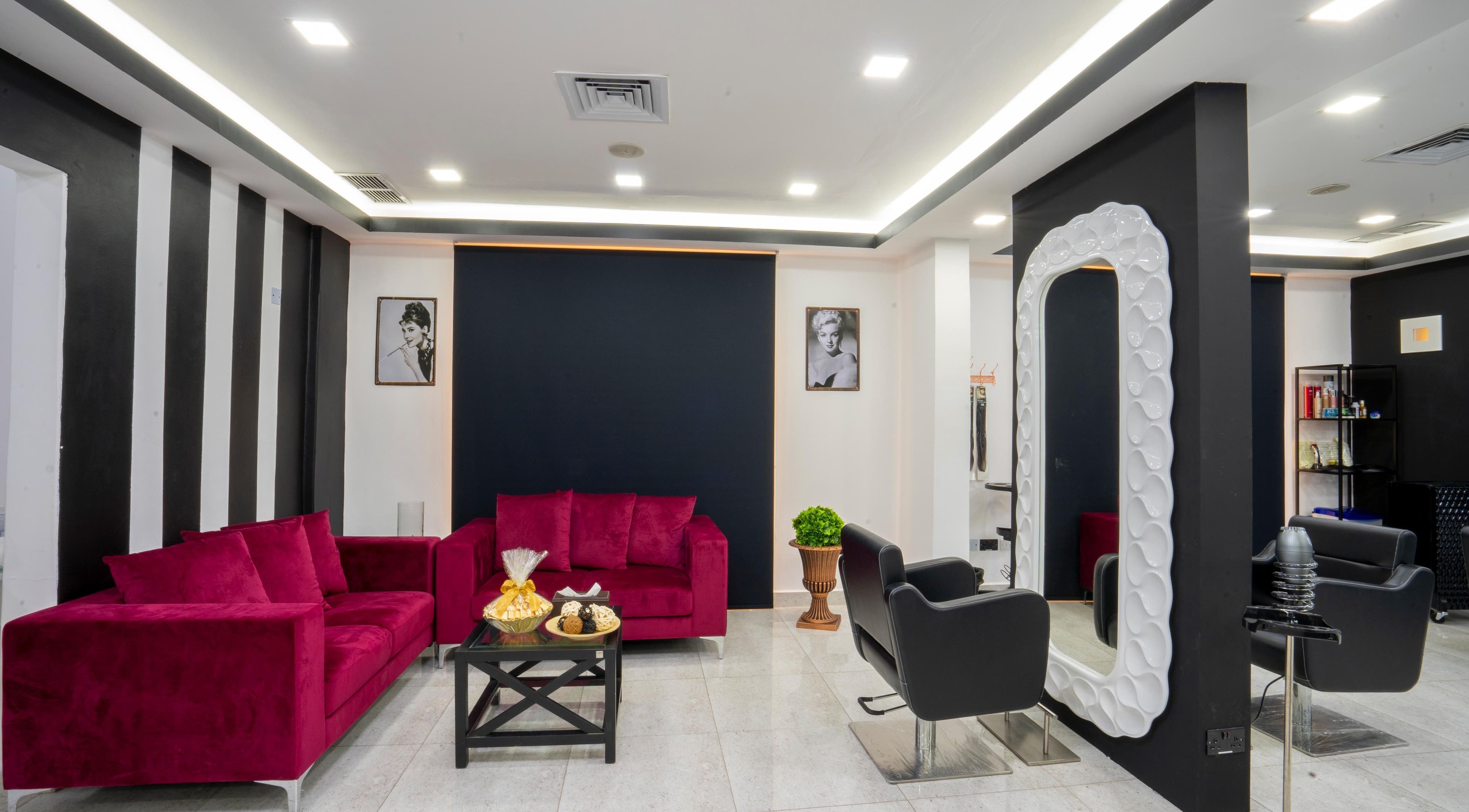 Sophisticated lounge at Beauty Lounge, Salmiya, Hawalli Governorate, KW with vibrant red sofas and modern décor.