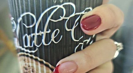Stylish red-manicured nails holding a coffee cup at Royal Beauty in Bloemfontein, Free State, ZA.
