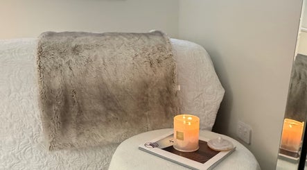 Cozy relaxation corner at Lash L'amour, Whangaparāoa, Auckland, NZ with a plush blanket and candle.