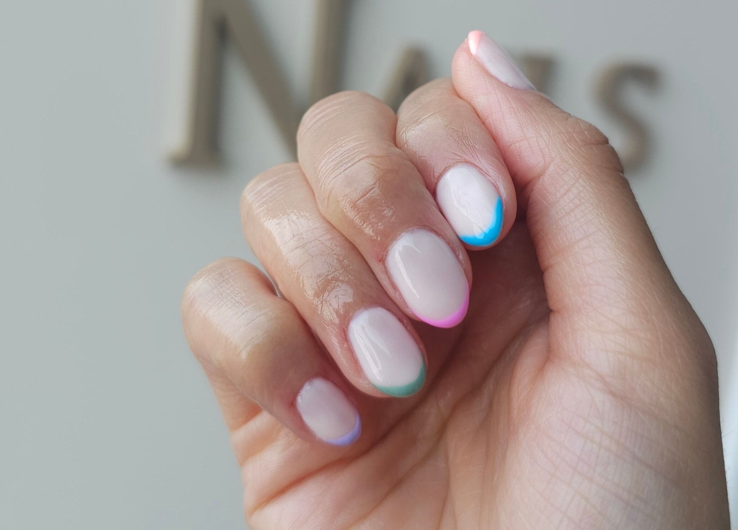 Hand with pastel multicolor manicure at Glass Skin Studio, Glasgow, Scotland, GB.