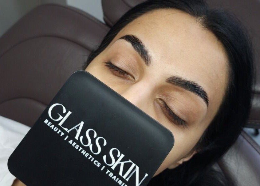 Client admires reflection at Glass Skin Studio, Glasgow, Scotland, GB during beauty treatment.