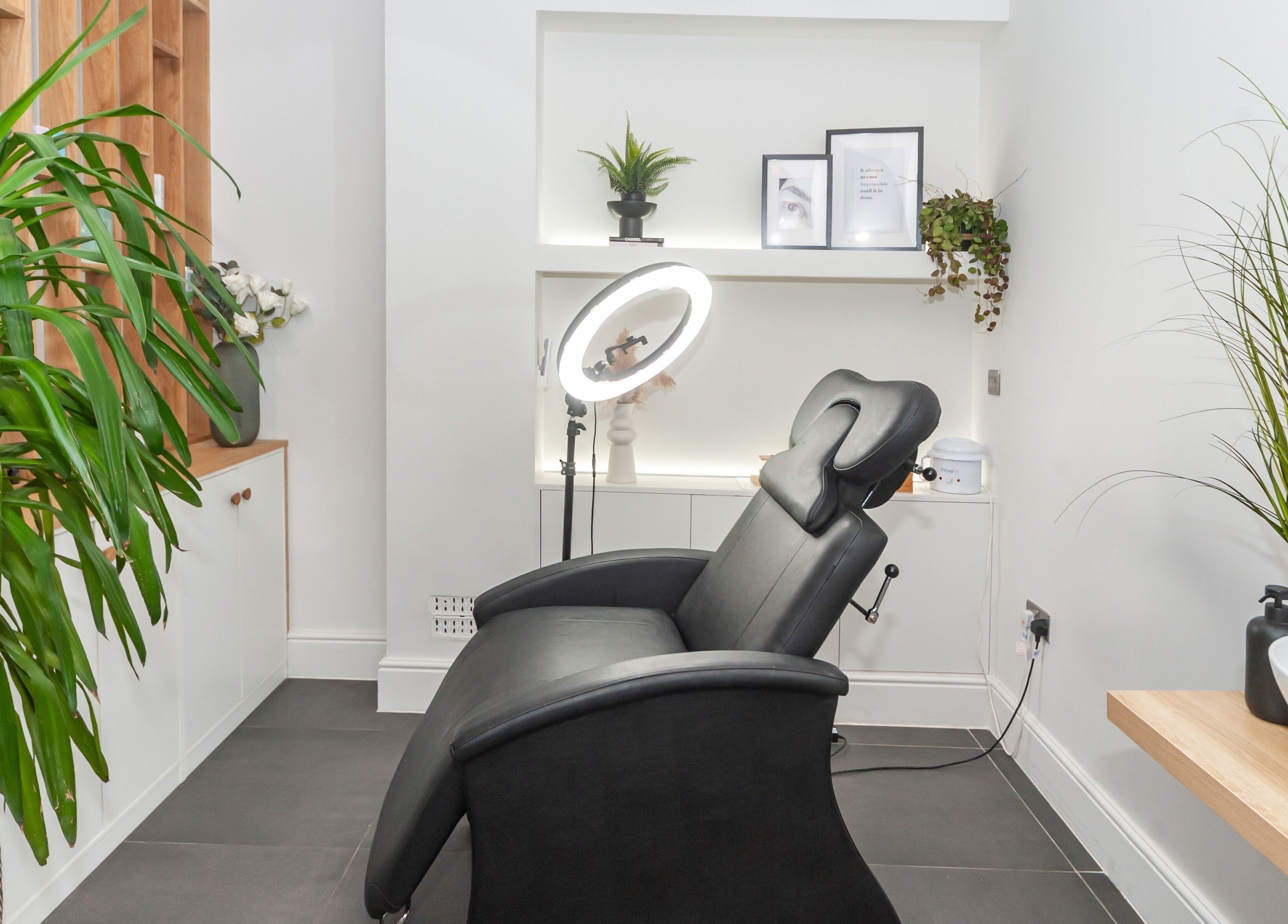 Cozy treatment room at Salon Mari Chiswick in London, England, GB, featuring a plush black chair and green plants.