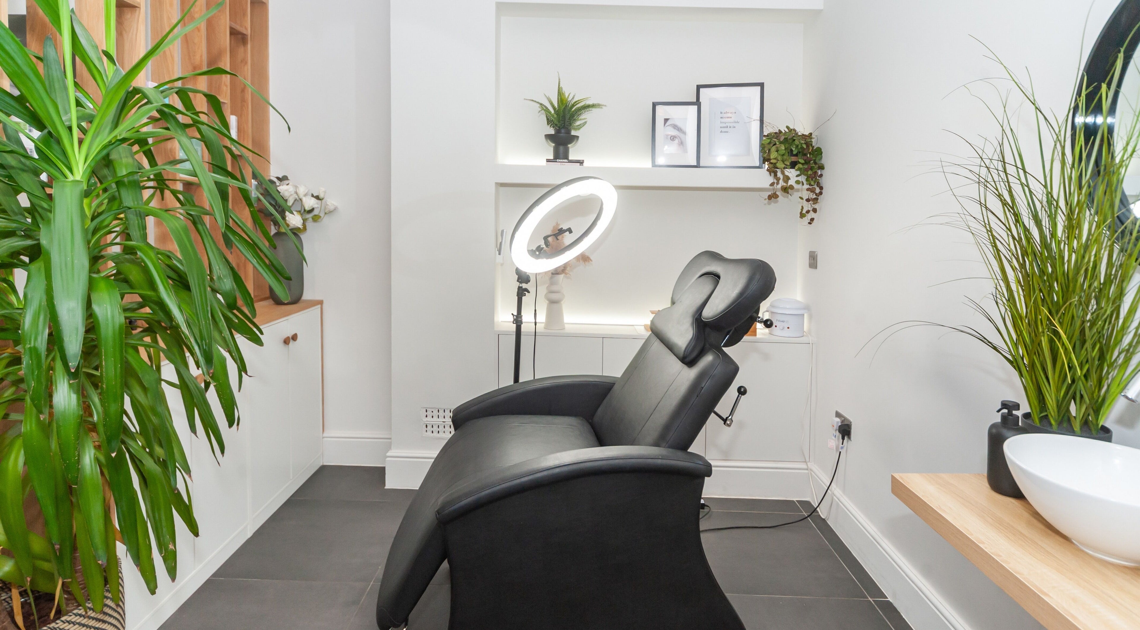 Cozy treatment room at Salon Mari Chiswick in London, England, GB, featuring a plush black chair and green plants.