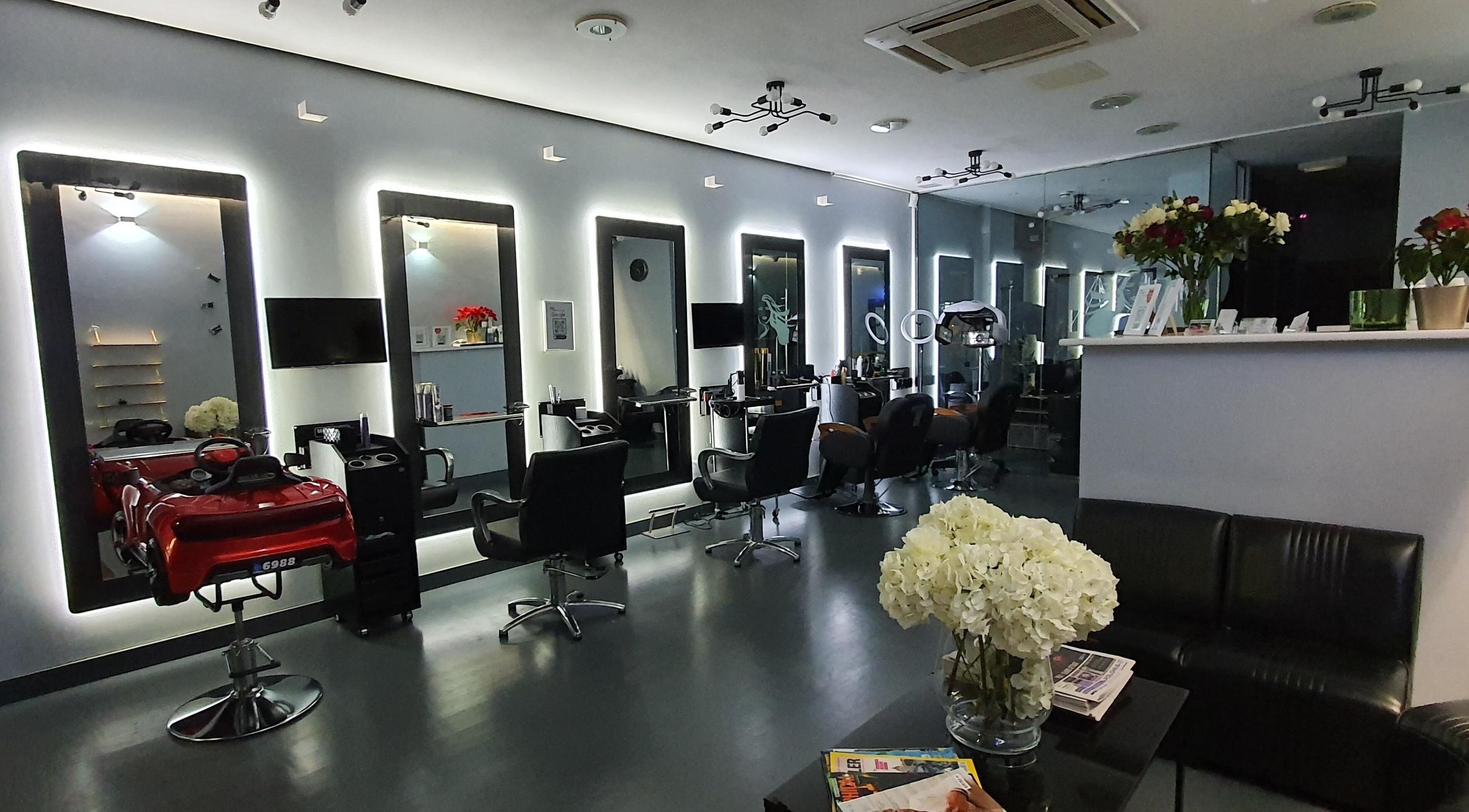 Inside view of Magnetic Unisex Hair Salon Ealing in London, England, GB, featuring stylish black chairs and mirrors.