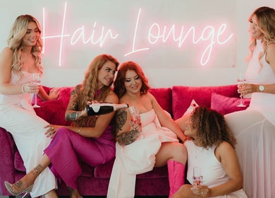 Friends enjoying a chic pink lounge at KG Hair Artistry, Bunbury, Wa, AU, with neon decor and celebration vibes.