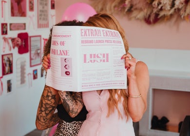 Lush Lane Hair Lounge guests enjoy reading themed paper in Bunbury, WA, AU, embracing chic pink decor.