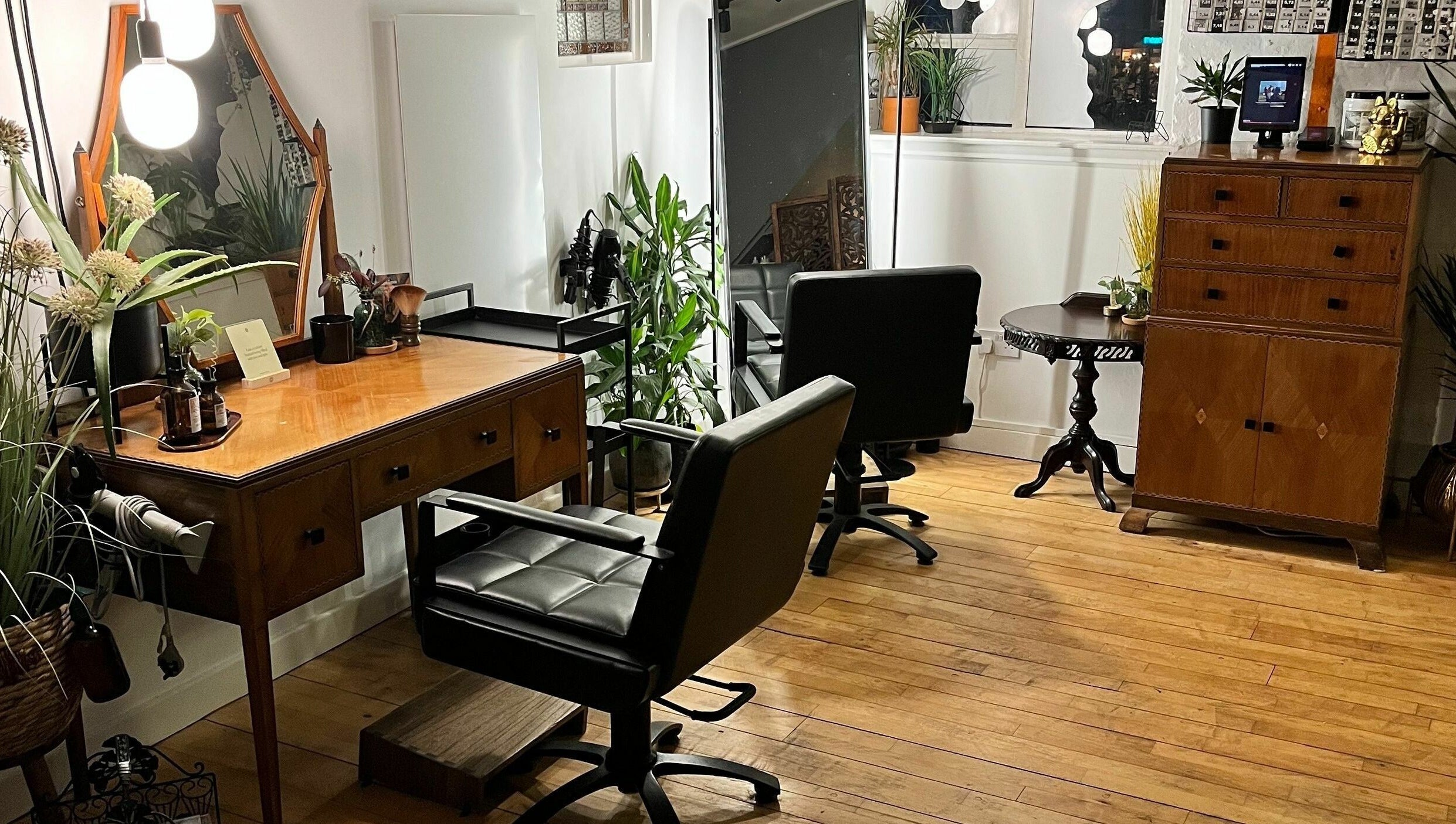 Charming salon interior at Sheep Hair, Glasgow, Scotland, GB featuring elegant styling stations and lush plants.