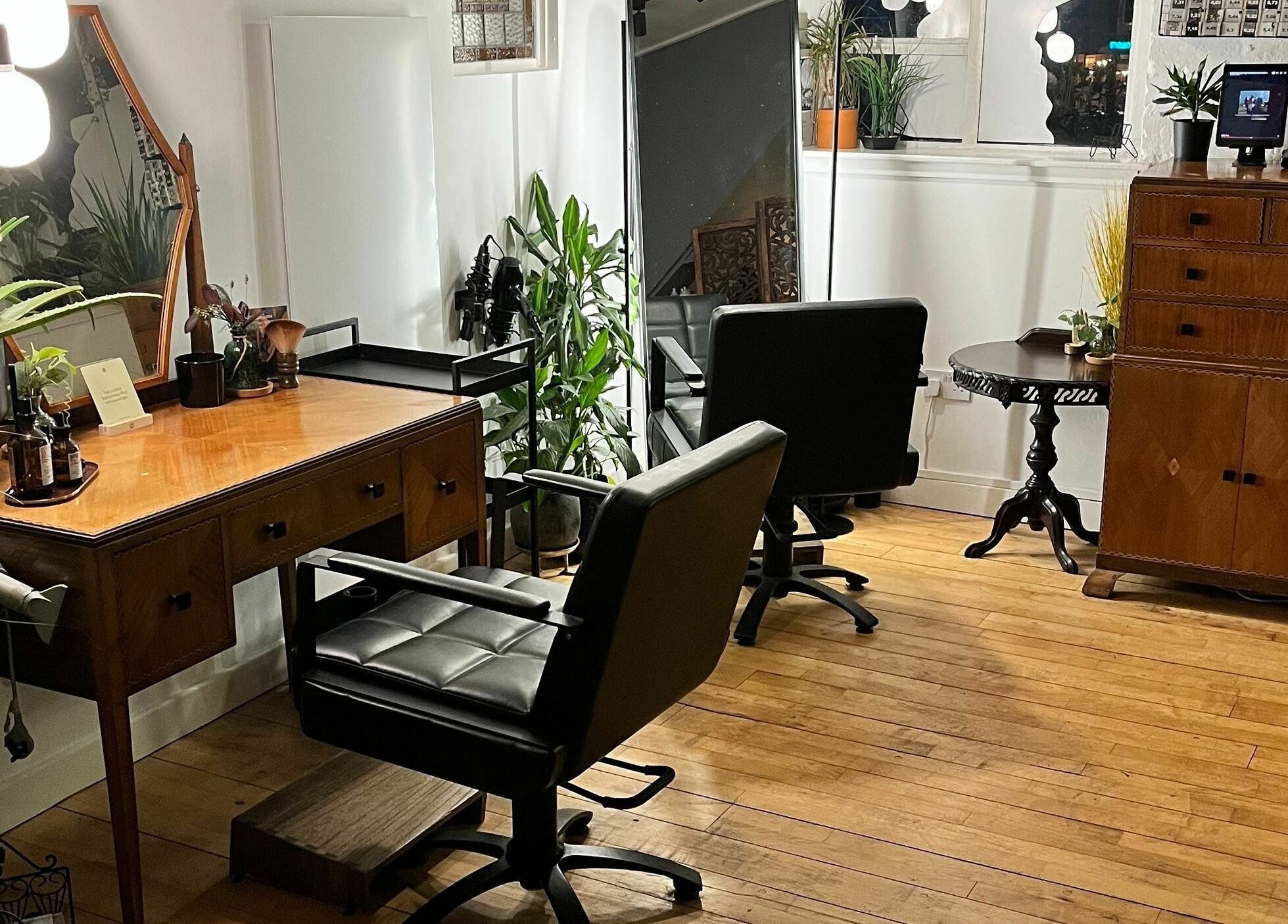 Charming salon interior at Sheep Hair, Glasgow, Scotland, GB featuring elegant styling stations and lush plants.