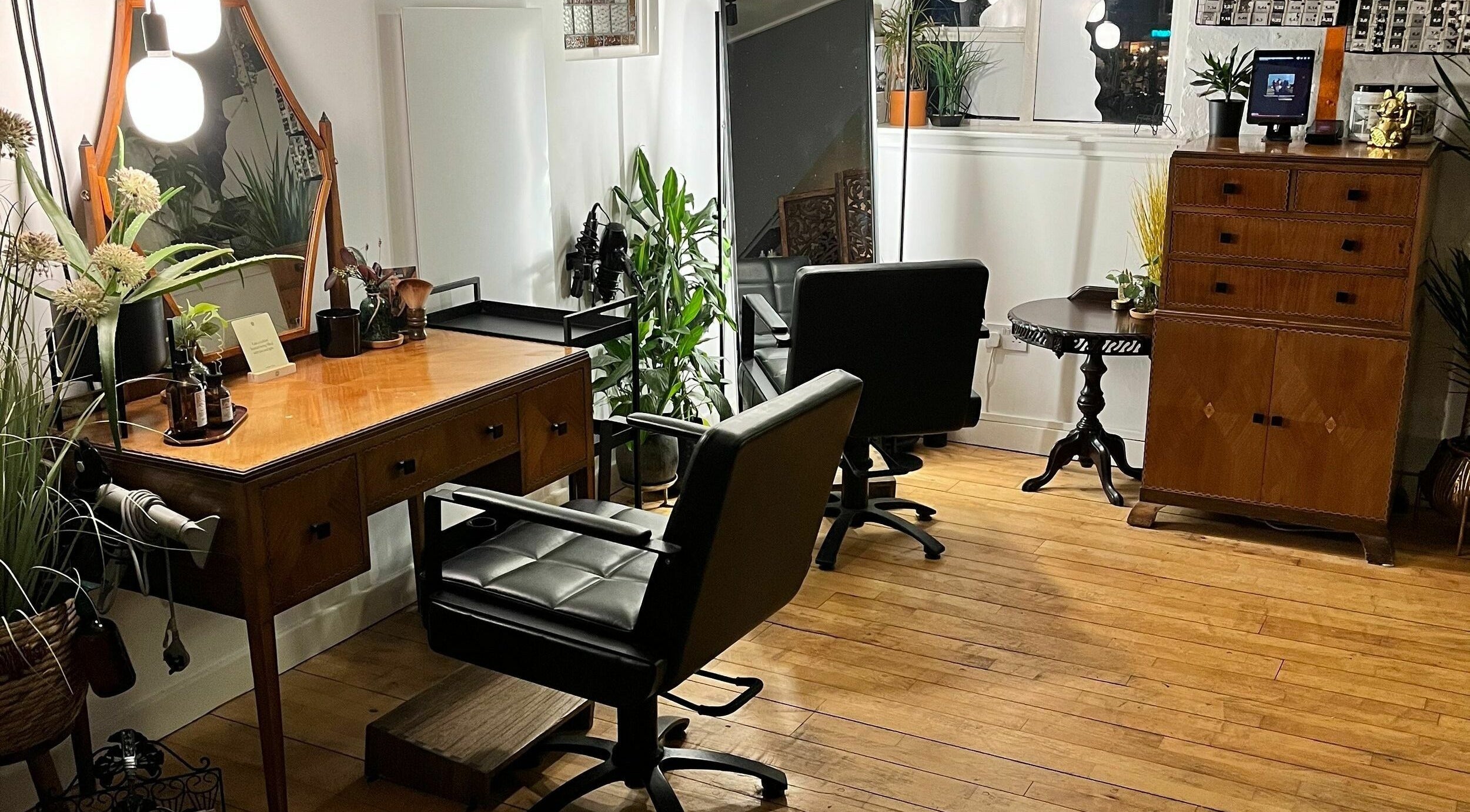 Charming salon interior at Sheep Hair, Glasgow, Scotland, GB featuring elegant styling stations and lush plants.