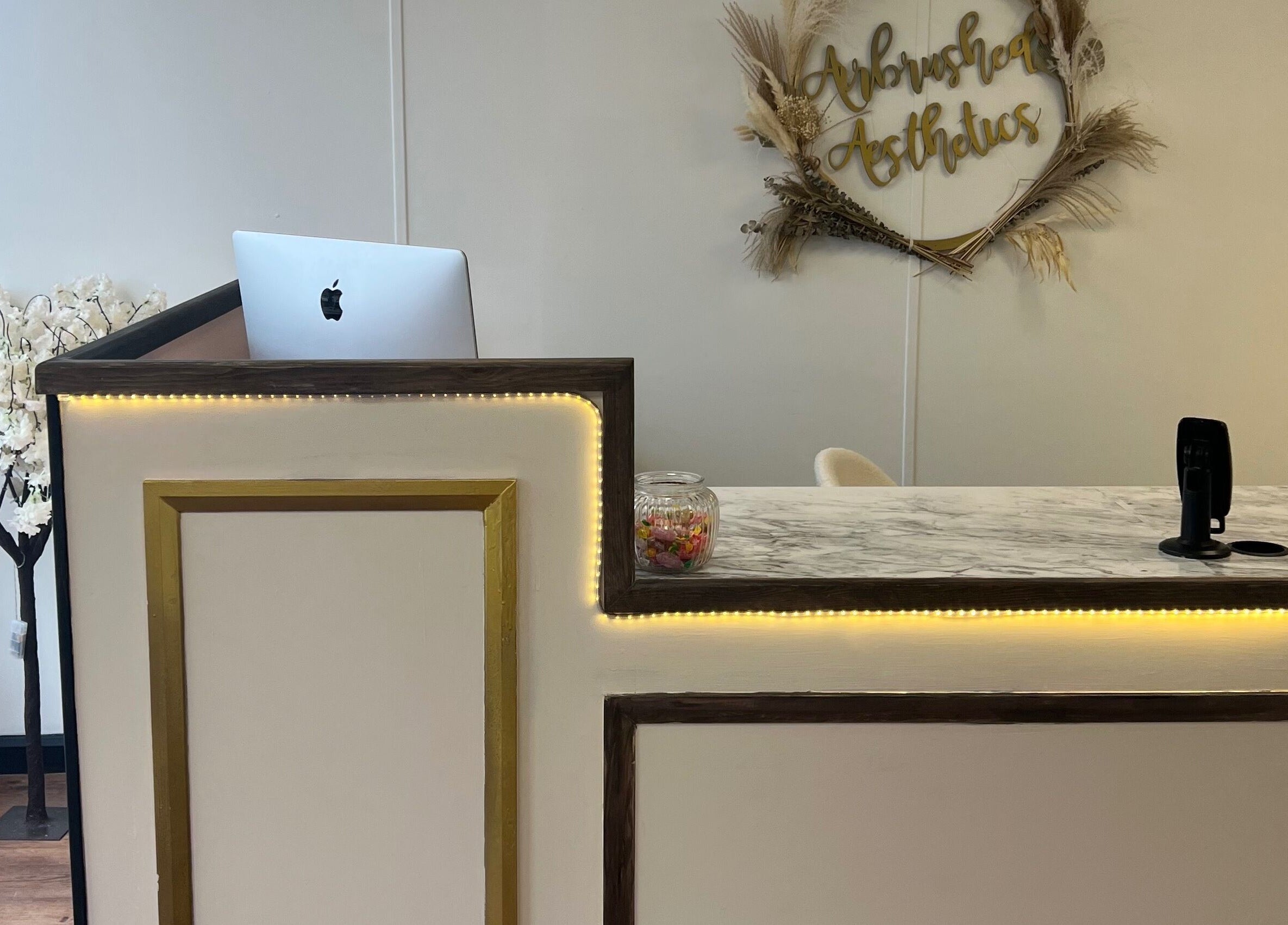 Reception desk at Airbrushed Aesthetics, Spalding, England, GB with modern decor and floral accents.