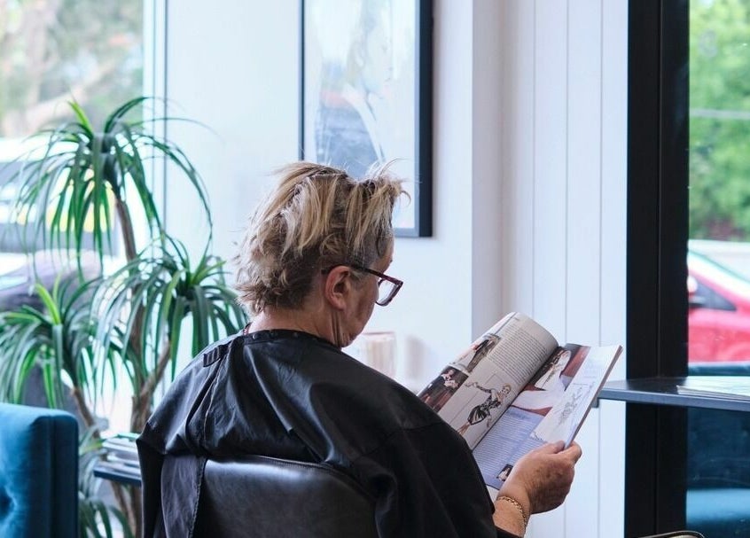 A customer enjoys a magazine in NUHAIRCO's serene salon, Mount Claremont, AU.