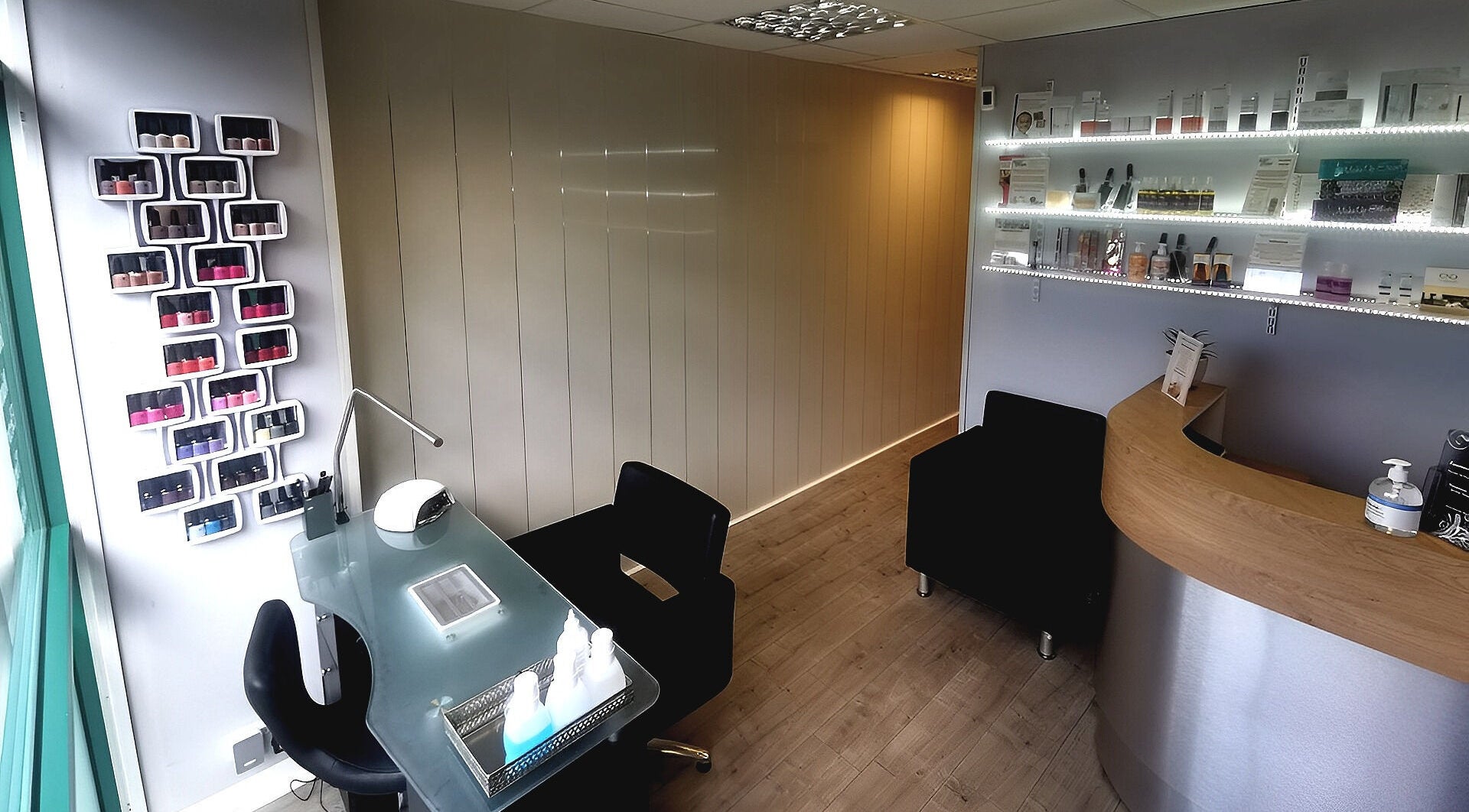 Inside Essential Beauty, Black Notley, England: modern nail bar with polished wooden reception and products displayed.
