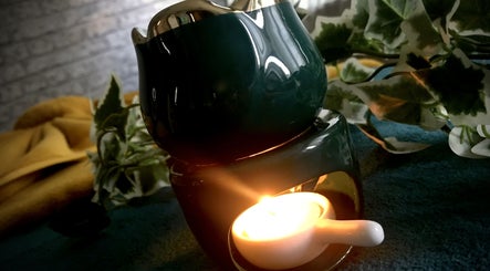 A serene candle light at Emerald Touch Massage, York, England, GB creating a calming ambiance with leafy decor.