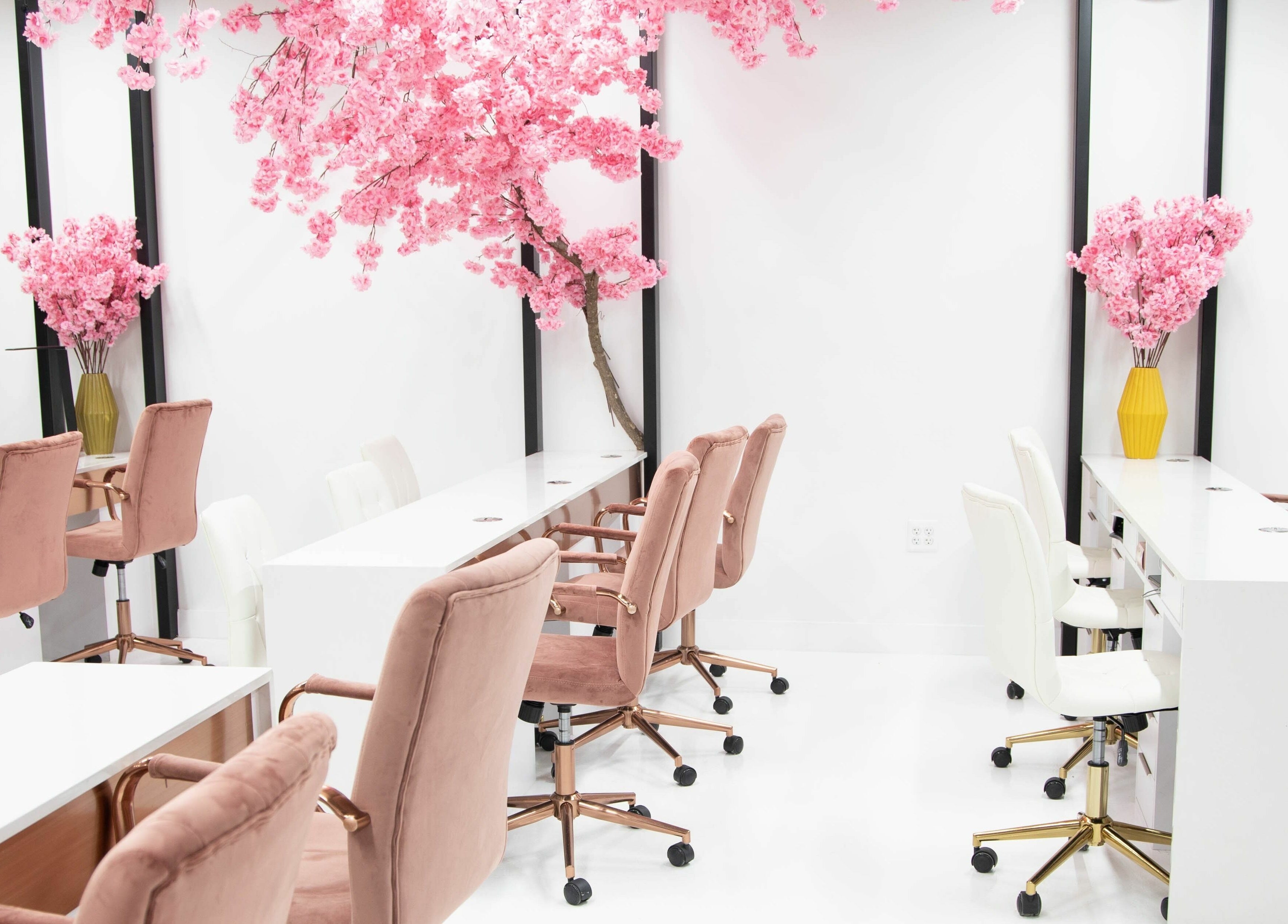 Elegant interior of Raizun Nail Spa in Fairfax, Virginia, US with pink chairs and cherry blossom decor.