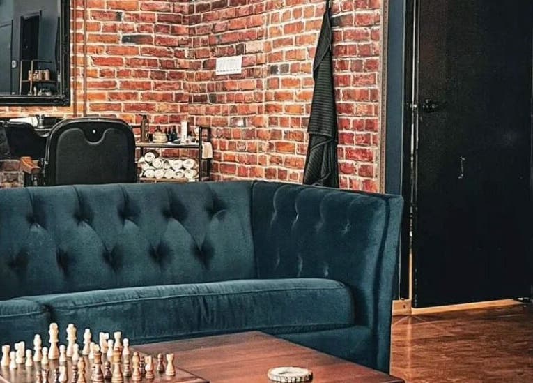 Stylish lounge area at Prohibition Barber & Bourbon Room in Canmore, Alberta, CA with plush seating and brick wall.