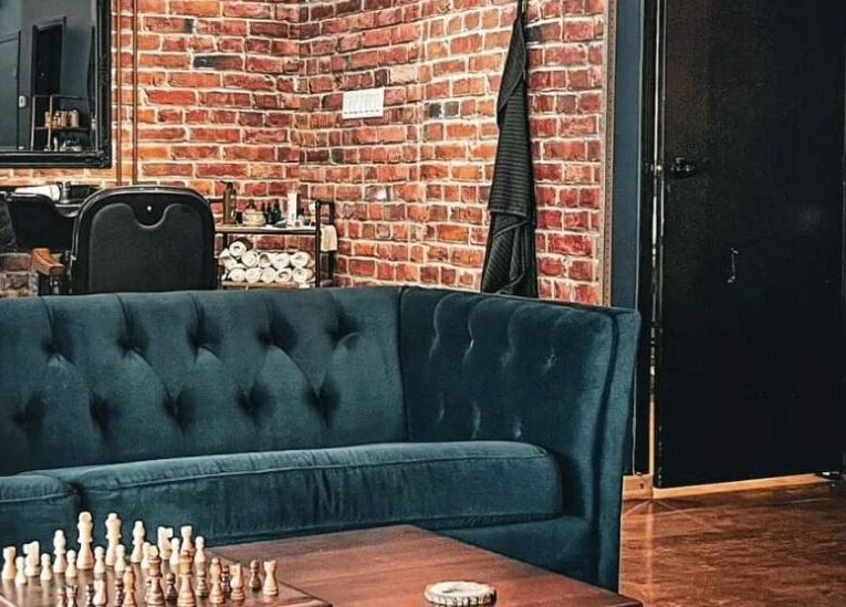 Stylish lounge area at Prohibition Barber & Bourbon Room in Canmore, Alberta, CA with plush seating and brick wall.