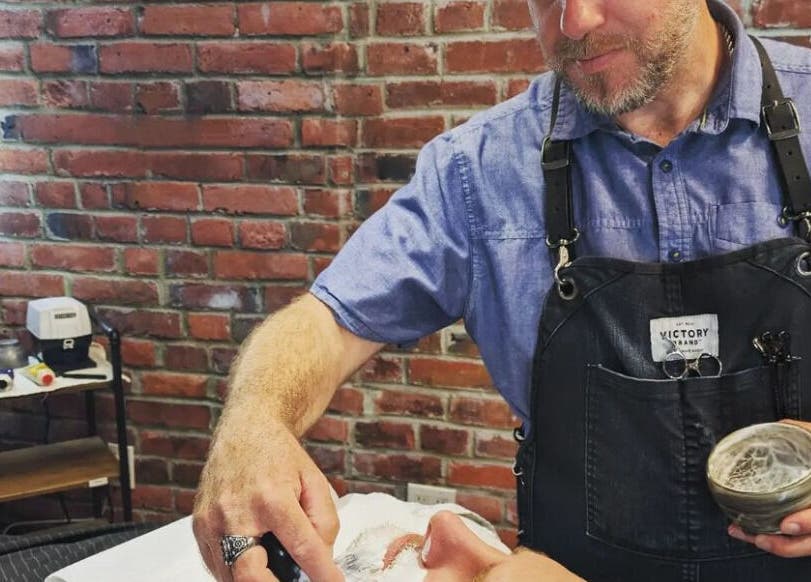 Barber performing a shave at Prohibition Barber & Bourbon Room in Canmore, Alberta, CA.