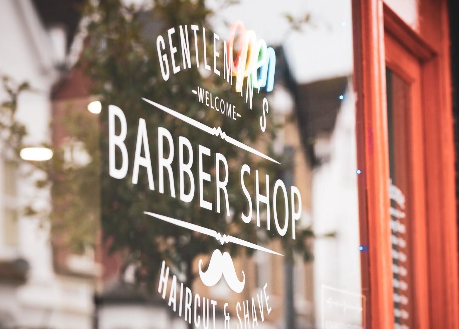 Front window of The Trimmers Wood Green barbershop in London, England, GB, with stylish lettering.
