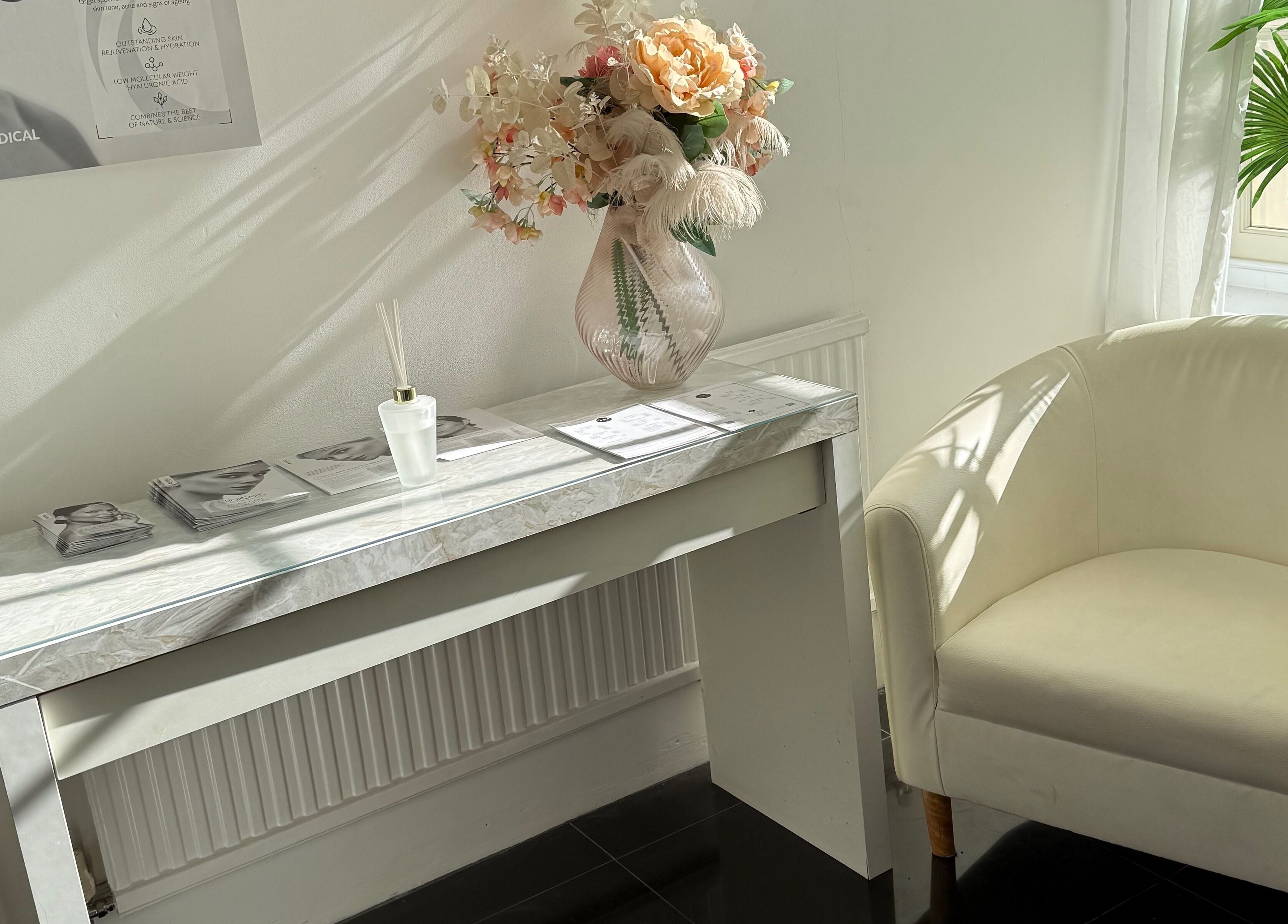 Elegant reception area at MBA Aesthetics & Training, Southampton, England, GB featuring a white chair and floral decor.