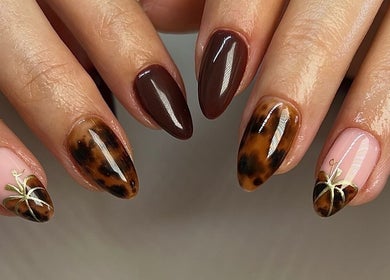Stunning nail art at Upperhand Beauty in Ampthill, GB featuring glossy brown and intricate designs.