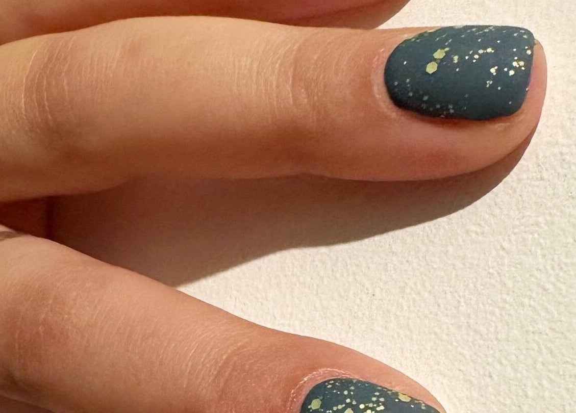 Stylish nail art with dark polish and speckles at Blossom Advanced Beauty, Selby, England, GB.