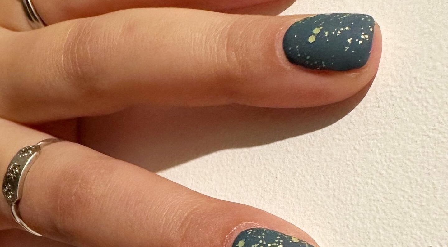 Stylish nail art with dark polish and speckles at Blossom Advanced Beauty, Selby, England, GB.