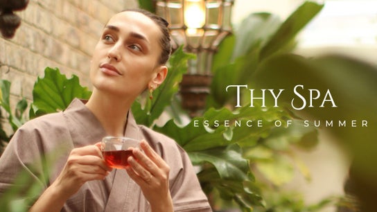Woman enjoying tea in lush garden at Thy Spa Bath, England, GB, embodying relaxation and tranquility.