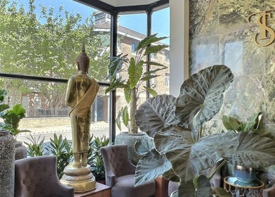 Relaxing seating area with lush plants and Buddha statue in Thy Spa Oxford, Oxford, England, GB.