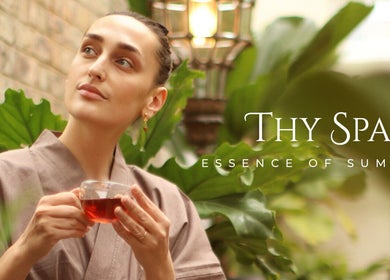 Relaxed woman with tea at Thy Spa Bath, Bath, England, GB, surrounded by lush greenery.