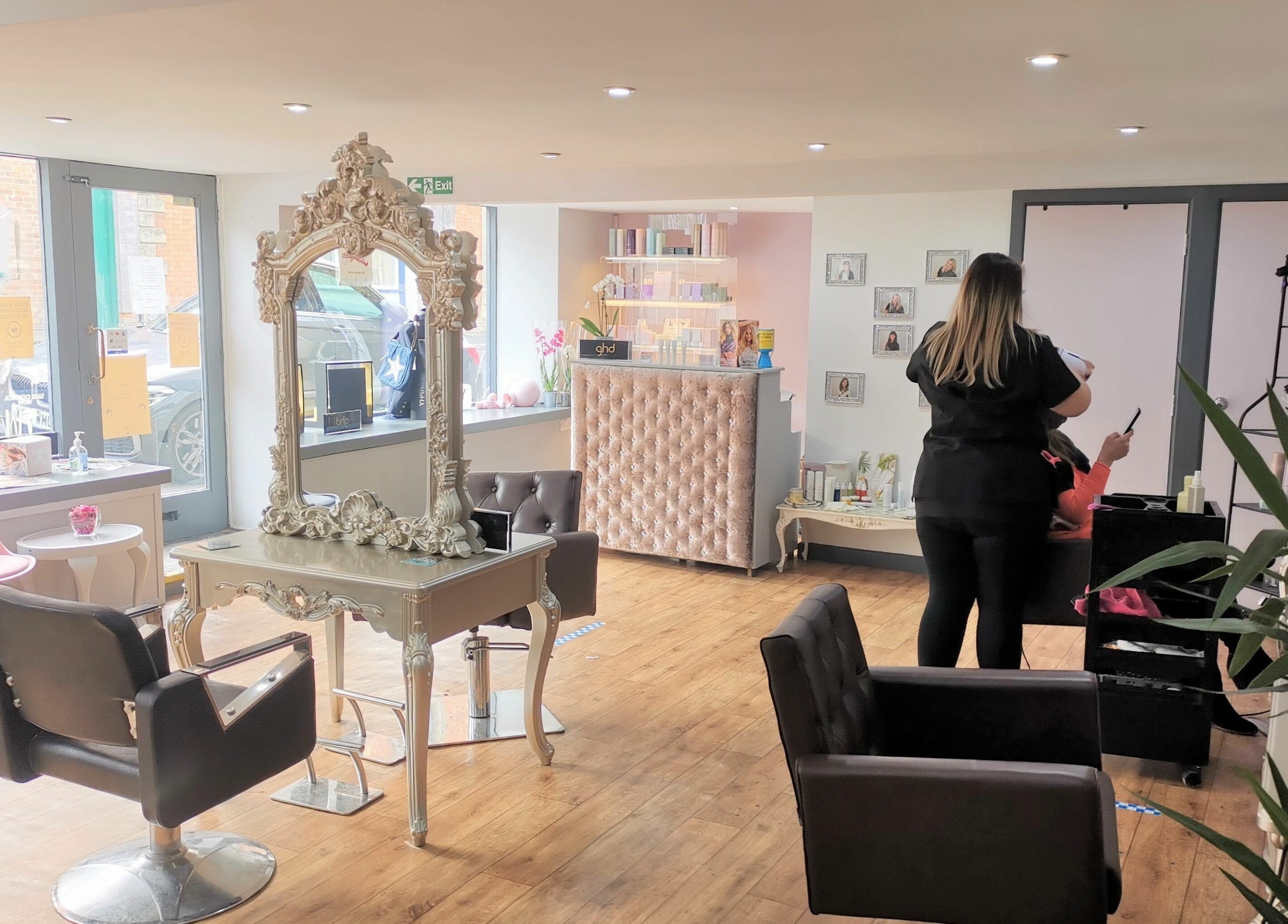 Bright interior of Lucy Jorge salon in Langport, England, GB with a stylist attending a client.