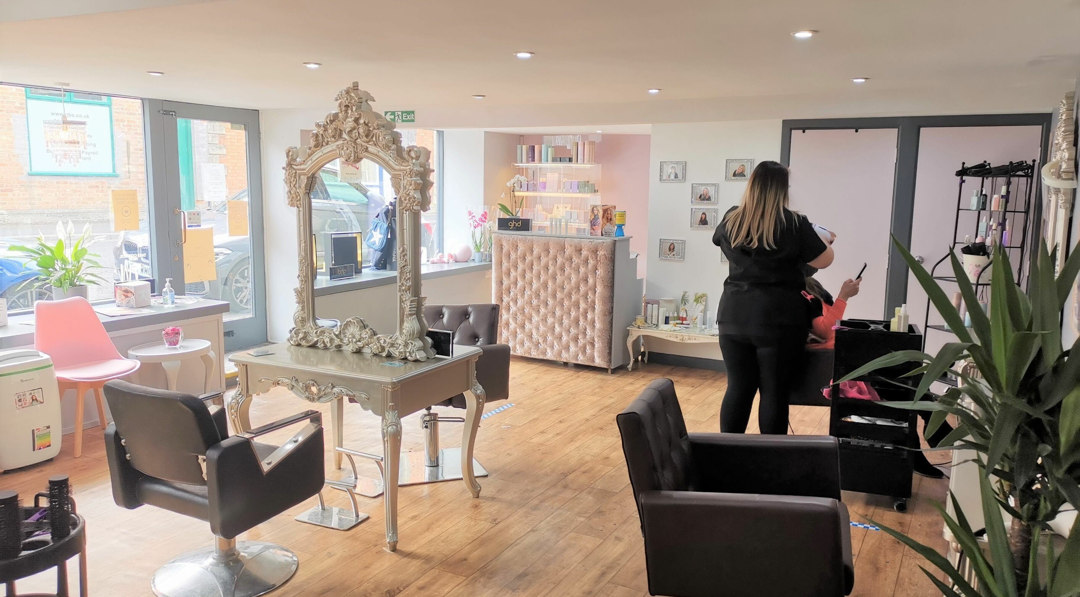 Bright interior of Lucy Jorge salon in Langport, England, GB with a stylist attending a client.