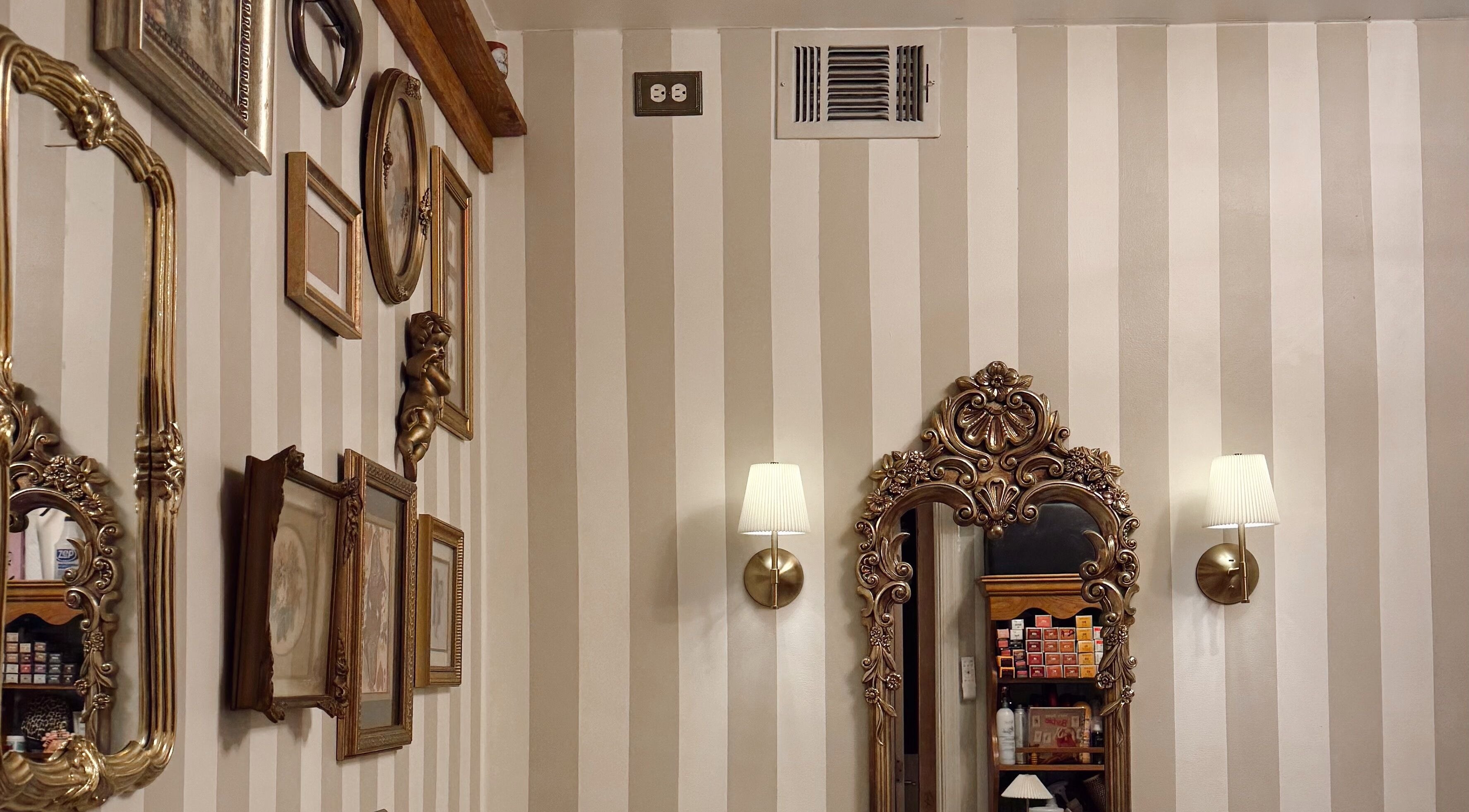 Ornate framed mirrors and decor on striped walls at Enhance Esthetics, Baltimore, Maryland, US.
