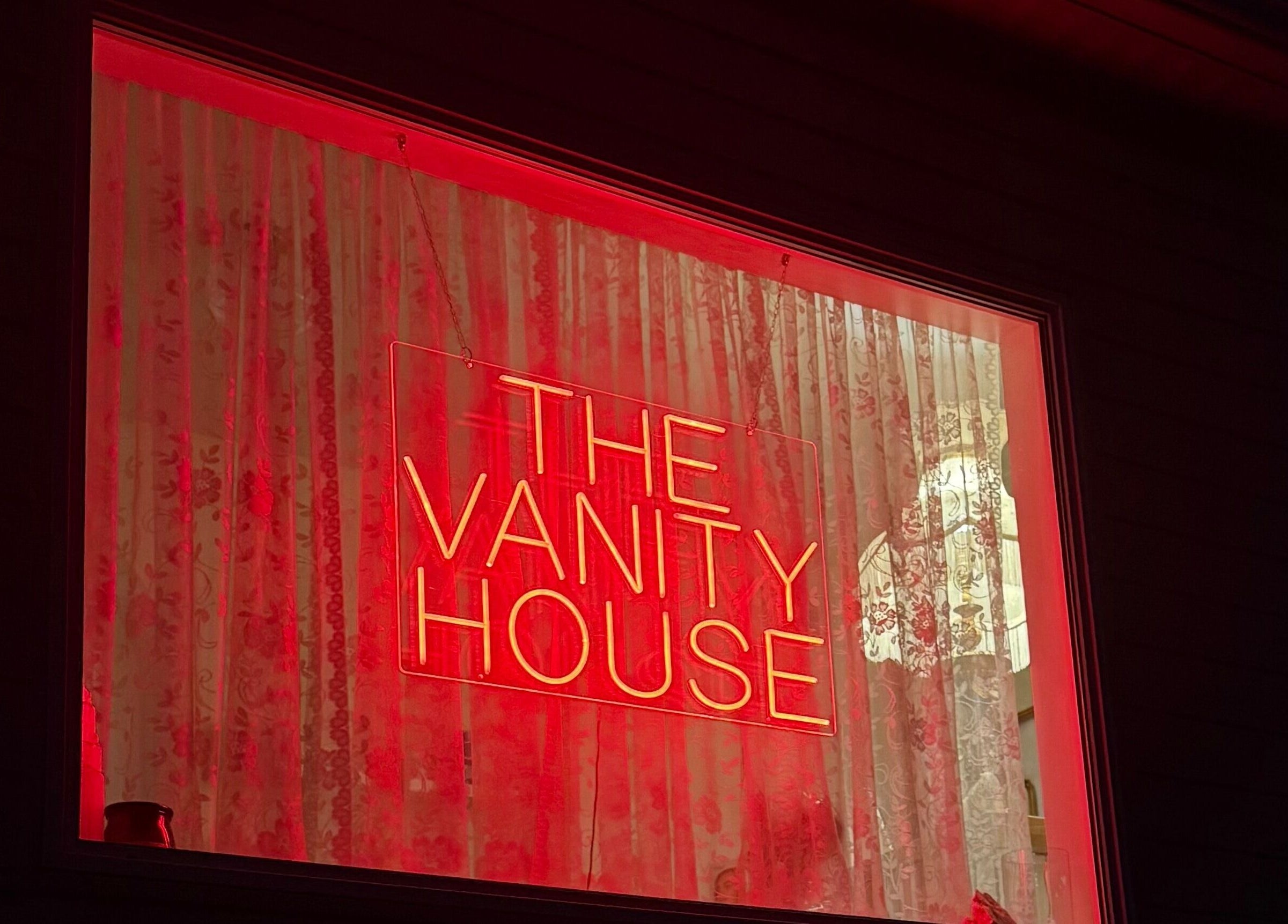 Red neon 'The Vanity House' sign glows warmly at Enhance Esthetics, Baltimore, Maryland, US.