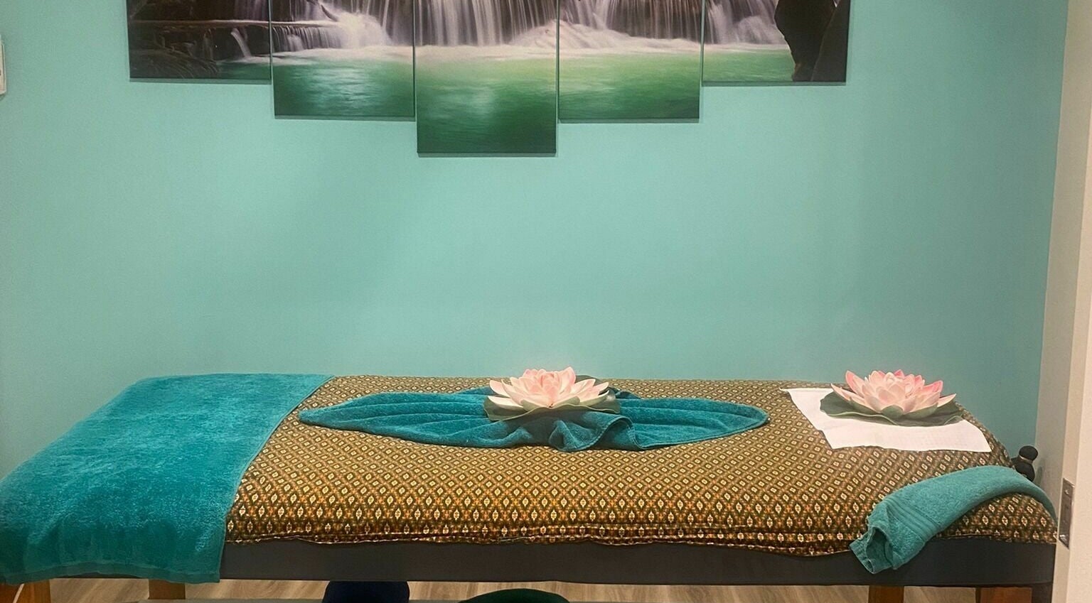 Massage table at Sawadee Cardiff in Cardiff, New South Wales, AU, with lotus decor and serene waterfall artwork.