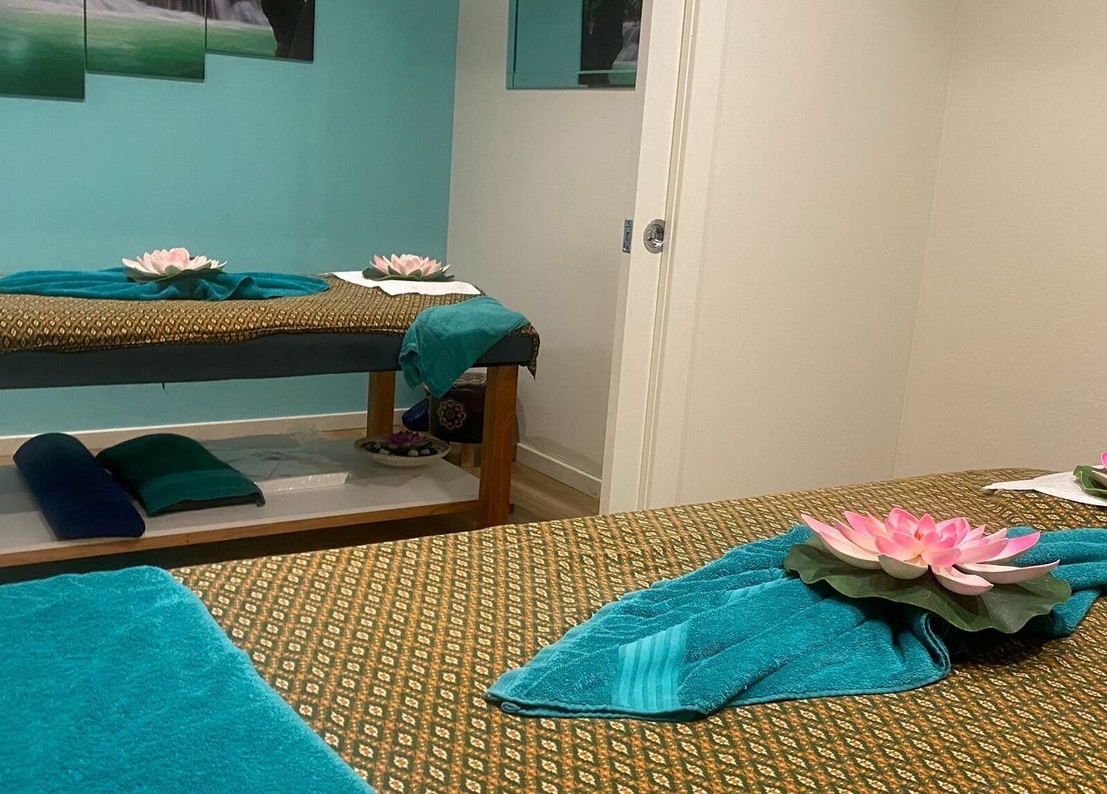 Relaxing massage room at Sawadee Cardiff, New South Wales, AU, adorned with lotus flowers and aqua towels.