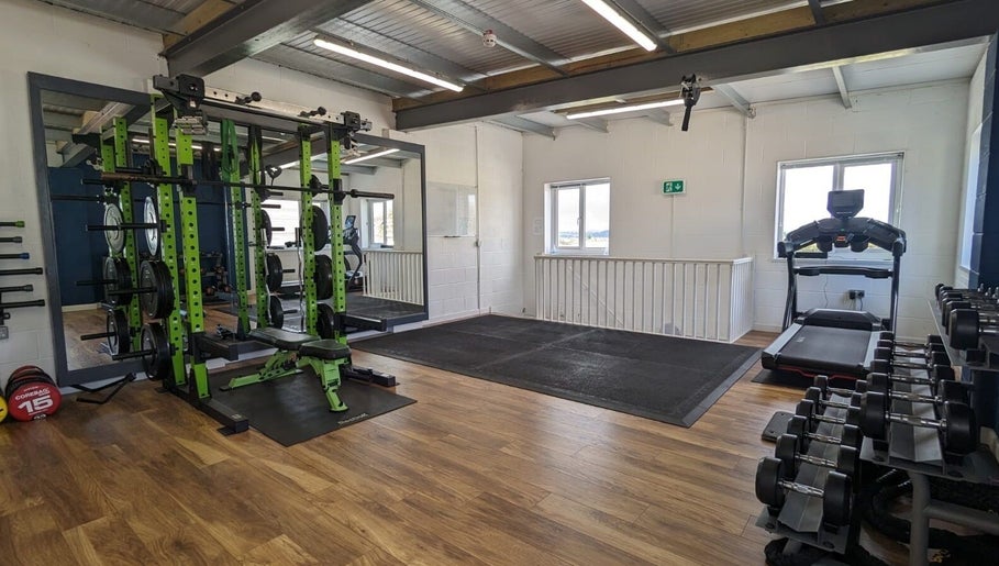 Modern gym area at Exe Fitness, Exmouth, England, GB, featuring weight racks and treadmill with ample lighting.