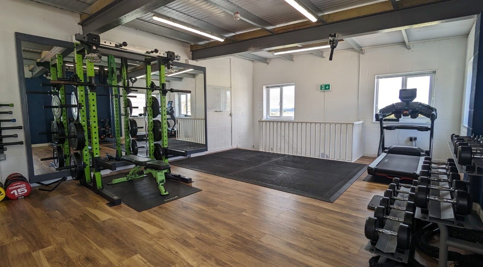 Modern gym area at Exe Fitness, Exmouth, England, GB, featuring weight racks and treadmill with ample lighting.