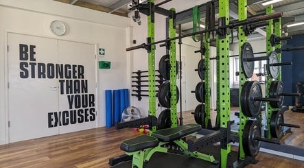 Weightlifting area at Exe Fitness in Exmouth, England, GB, featuring motivational wall art and modern equipment.