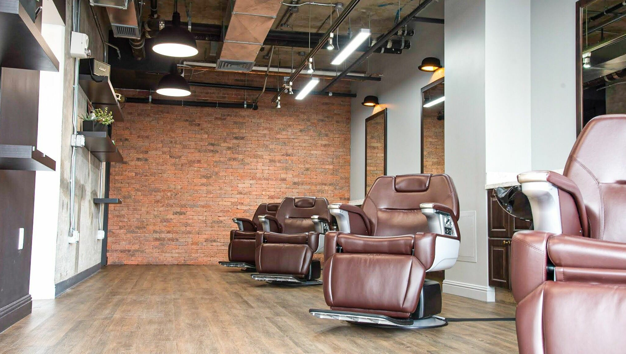 Modern barber chairs at Men's Grooming Salon SKY, Honolulu, Hawaii, US with exposed brick wall.