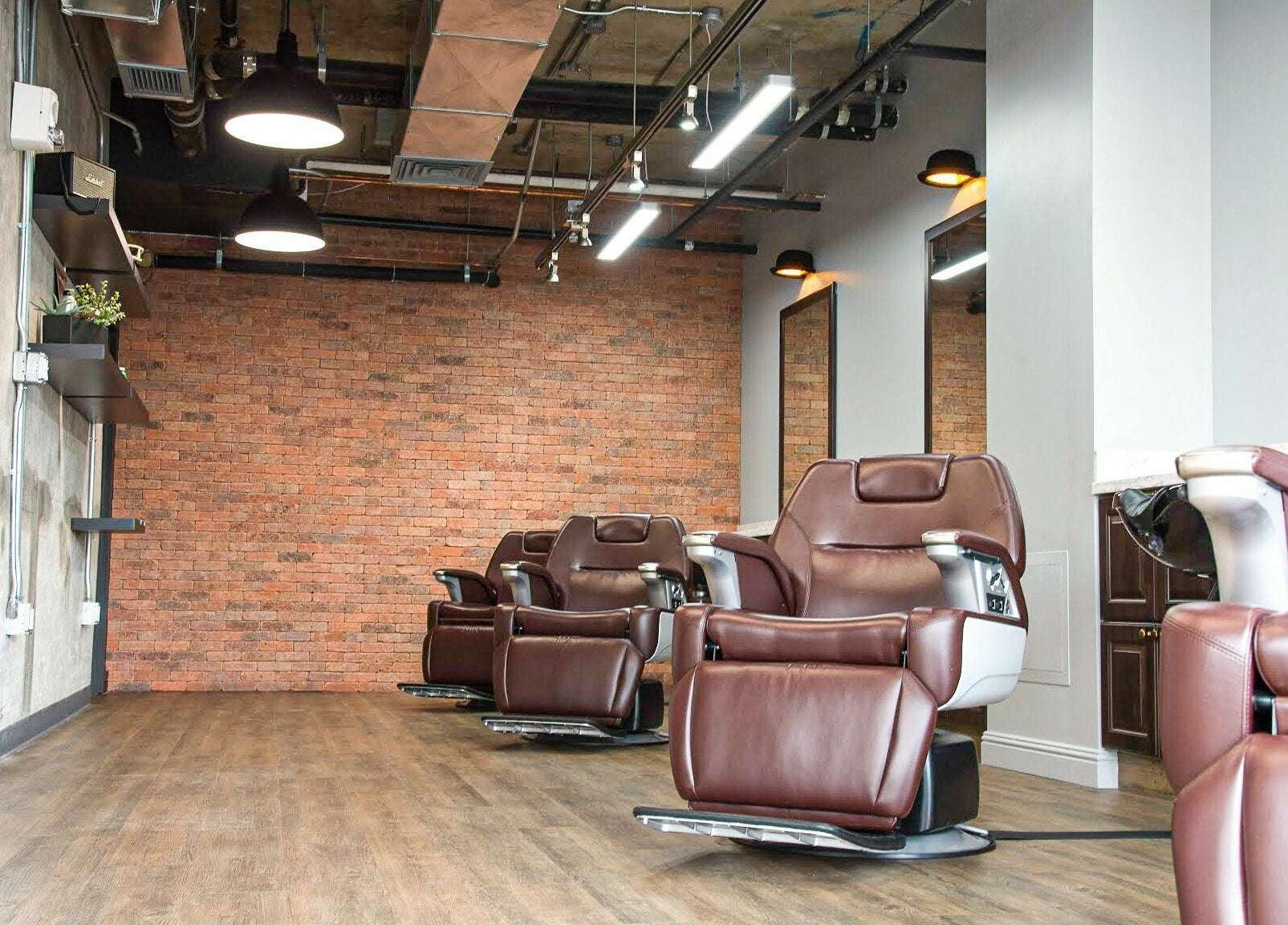 Modern barber chairs at Men's Grooming Salon SKY, Honolulu, Hawaii, US with exposed brick wall.