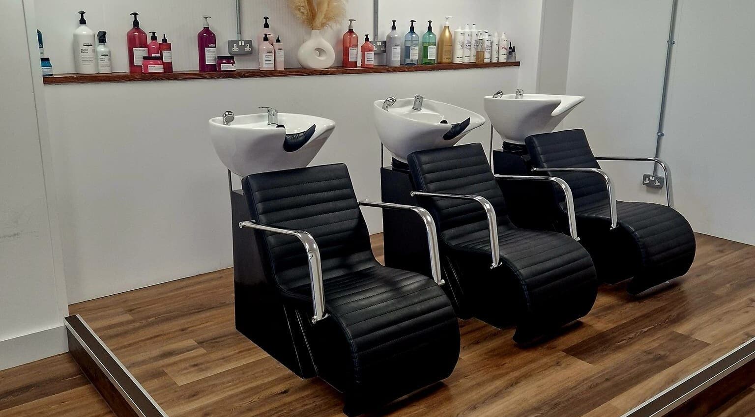 Modern hair washing stations at Blend in Bury St Edmunds, England, GB, showcasing sleek black chairs.